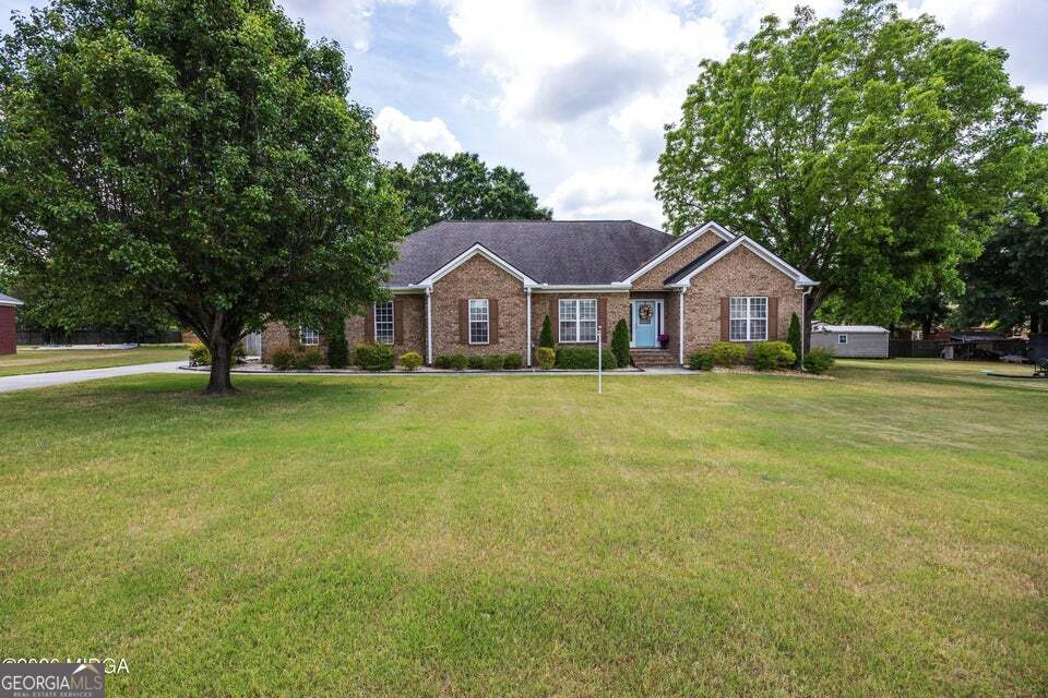 Large front yard at 411 Dixieland Drive in Byron GA featuring beautiful brick home with landscaped lawn and private setback from the street