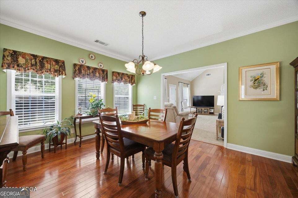 Formal dining room at 411 Dixieland Drive in Byron GA featuring hardwood floors, large windows, natural light, and elegant open-concept design