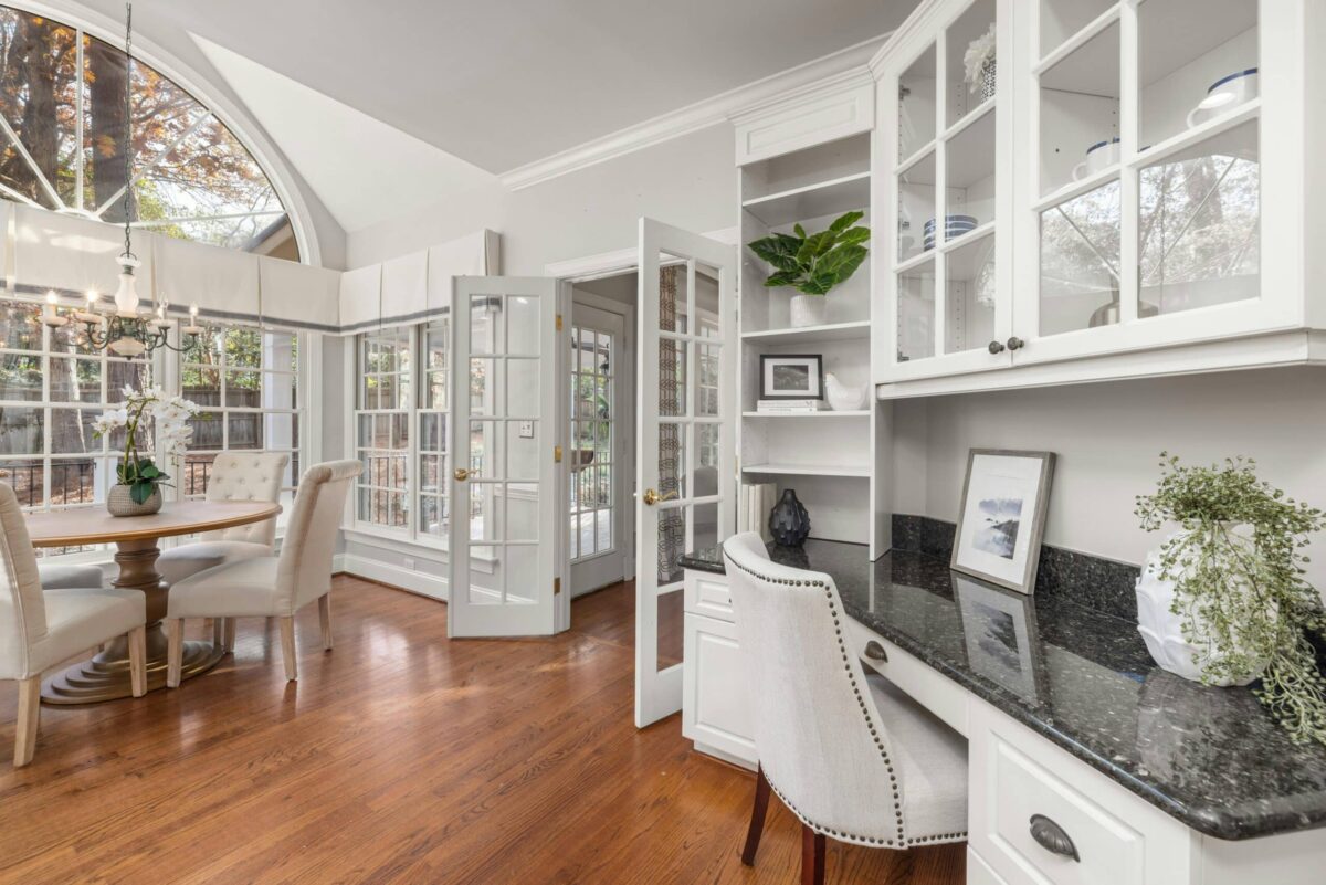 Bright and elegant home office and breakfast area with vaulted ceilings, large arched windows, hardwood floors, built-in cabinetry, and abundant natural light.