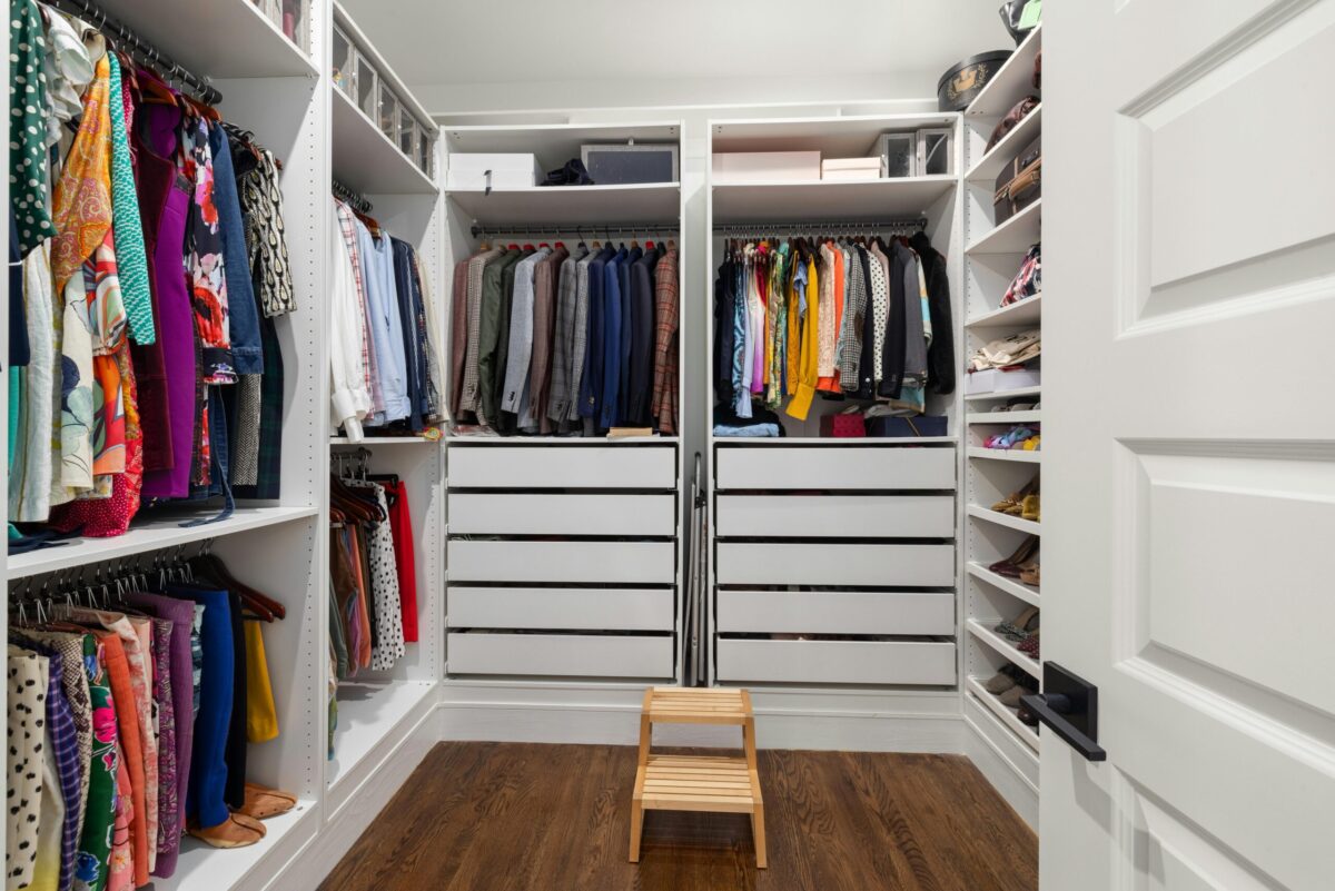 Spacious custom walk-in closet with built-in shelving, organized hanging storage, hardwood floors, and dedicated shoe and accessory storage areas.