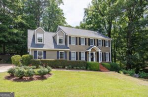 Front exterior view of 1301 Craddock Way in Rivoli Lakes, featuring a traditional two-story home with a two-car garage, mature landscaping, and a wooded North Macon setting.