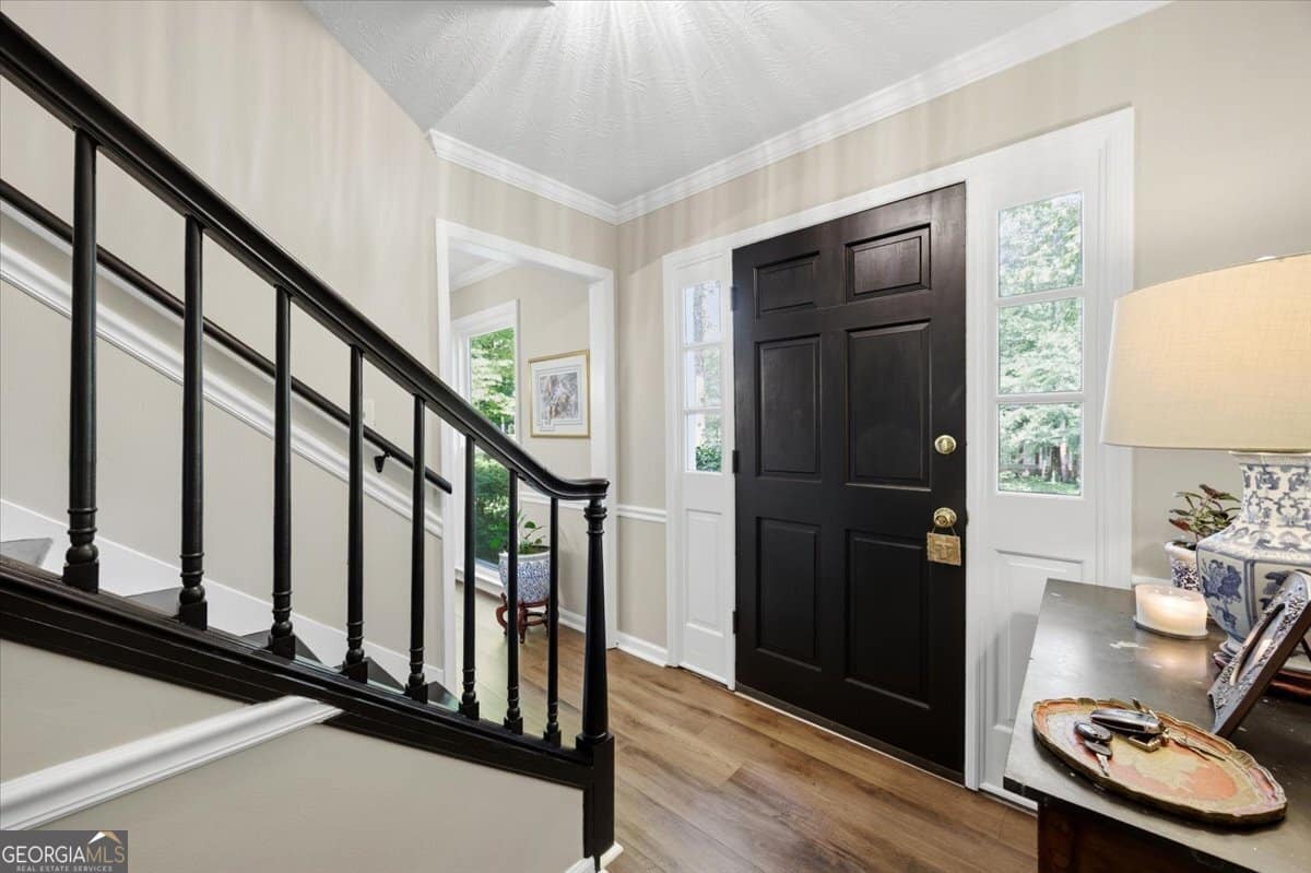 Updated foyer and staircase inside 1434 Craddock Way in Macon GA featuring luxury vinyl plank flooring, crown molding, and stylish entryway design.