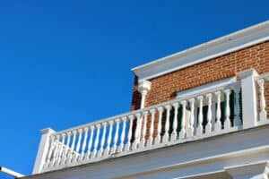 Historic brick home with white balcony railing showcasing classic architectural details and curb appeal