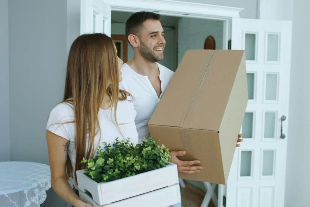 Happy couple carrying moving boxes into their new home