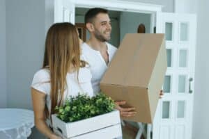 Happy couple carrying moving boxes into their new home