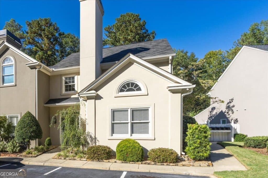 Front exterior of 153 Lokchapee Landing in Macon GA, featuring a stucco facade, arched window, landscaped shrubs, and a side walkway.