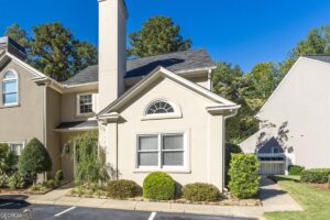 Front exterior of 153 Lokchapee Landing in Macon GA, featuring a stucco facade, arched window, landscaped shrubs, and a side walkway.
