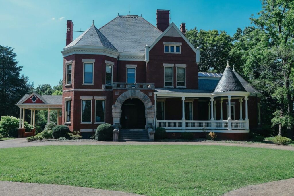 Historic Victorian Home in Macon Georgia - Patti Chapman Real Estate™ Historic red brick Victorian home with turret, wraparound porch, and mature landscaping